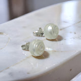 Hand-carved freshwater pearl earrings with rose-like spiral design set on sterling silver studs