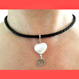 Black leather choker necklace with a white heart pendant and silver 'Y' charm on a person's neck.