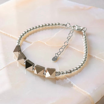 Swarovski crystal spike bracelet with sterling silver beads and adjustable chain clasp on neutral stone background