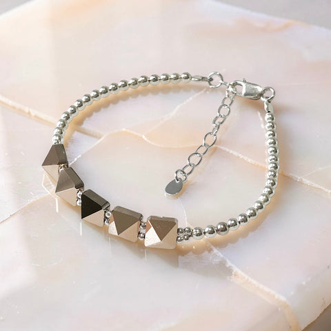 Swarovski crystal spike bracelet with sterling silver beads and adjustable chain clasp on neutral stone background