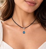 Swarovski blue teardrop crystal pendant with sterling silver bail on a black cord necklace, model wearing the necklace.