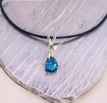 Swarovski blue teardrop crystal pendant with sterling silver bail on a black cord necklace, model wearing the necklace.