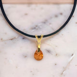 Swarovski orange teardrop crystal pendant with sterling silver bail on a black cord necklace, model wearing the necklace.