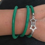 Green bracelet with a silver star-shaped charm on a wrist against a dark background