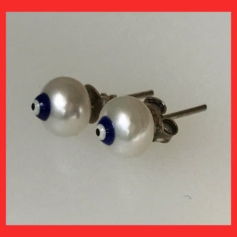 A pair of freshwater pearl earrings with a sterling silver pin and butterfly, featuring an evil eye sign.
