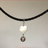 Necklace with a heart-shaped pendant and 'Y' charm on a black cord against a neutral background